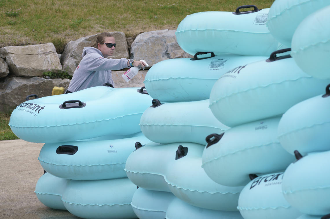 A lifeguard disinfects mattresses used to slide down a water slide in Bromont, Que., in June 2020 as water parks reopened in the province.