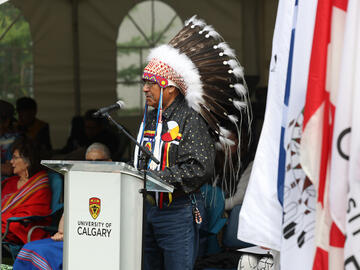 Elder Dr. Clarence Wolf Leg addresses graduates and guests at the Indigenous Graduation Celebration
