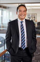 portrait of a man in business attire, standing in a windowed room