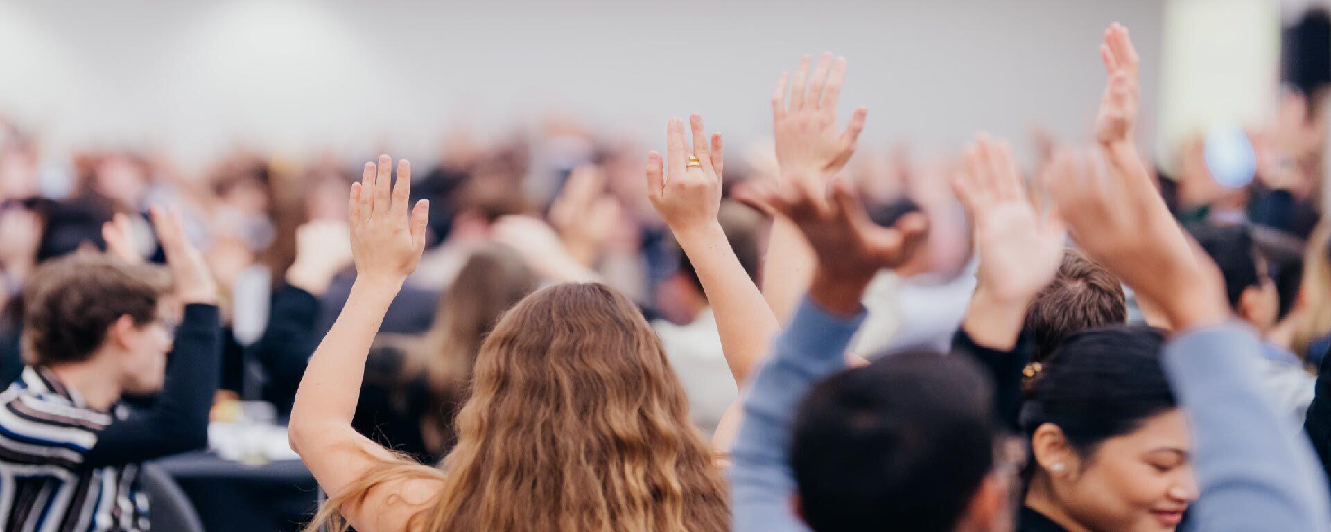 Students and community members raising hands and engaging in a Haskayne Centres event